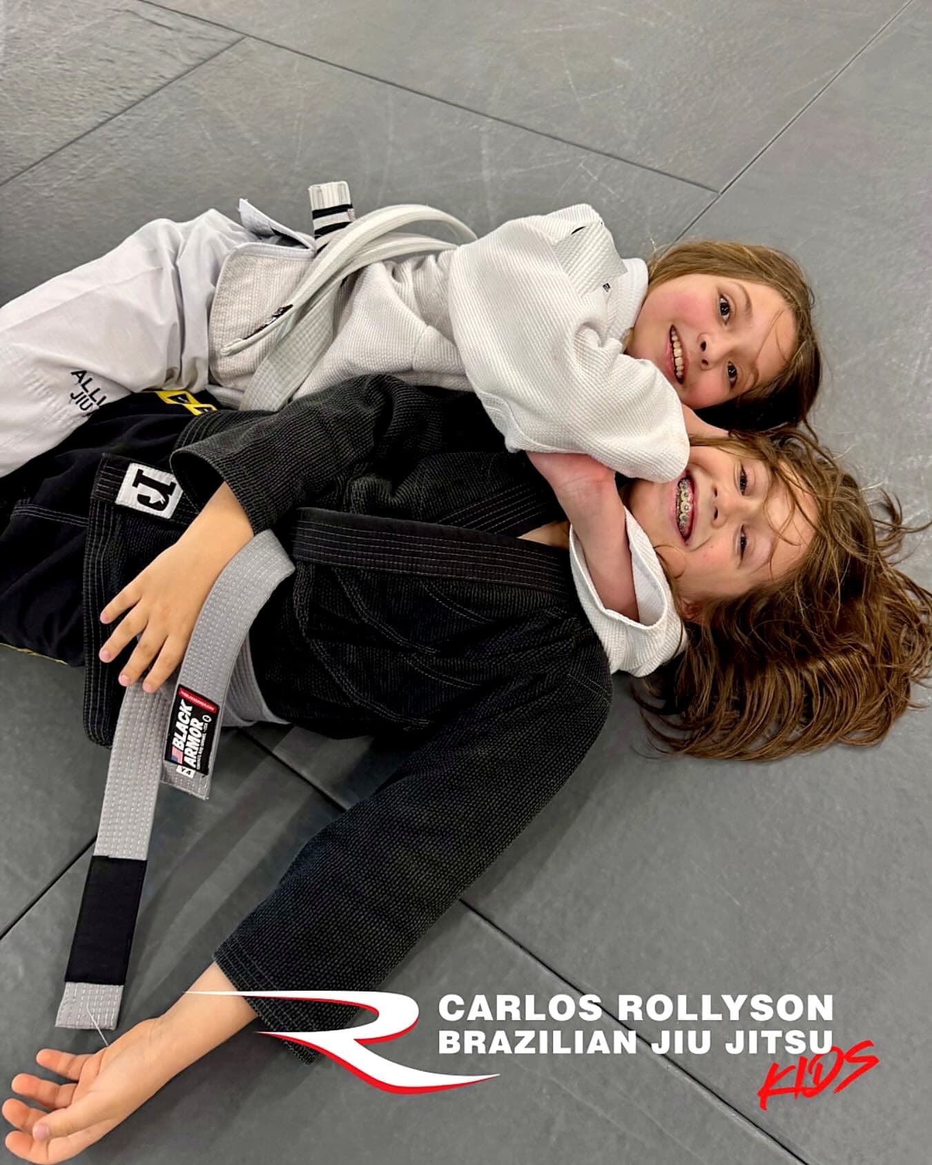 Two kids smiling while grappling in a Young Warriors class at Rollyson BJJ